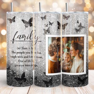 May include: A silver glitter tumbler with a black and white butterfly design and the word "family" defined as "the people you live for, laugh with and love most." The tumbler features a photo of a family with a mother, father, and child.