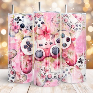 Puede incluir: Un juego de tres vasos de acero inoxidable con un diseño floral rosa y un mando de videojuegos. El diseño presenta mandos rosas y blancos y flores rosas sobre un fondo rosa. El texto "Mamaya Tumblers" está en la parte inferior.