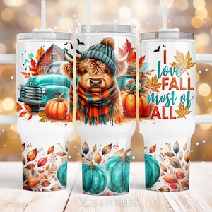 May include: White tumbler with a fall theme. The tumbler features a highland cow wearing a scarf and hat, a blue truck, pumpkins, and fall leaves. The text on the tumbler reads "I love fall most of all".