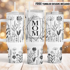 May include: White stainless steel tumbler with a black and white floral design and the word "MOM" in a geometric frame. The tumbler has a lid and a handle.