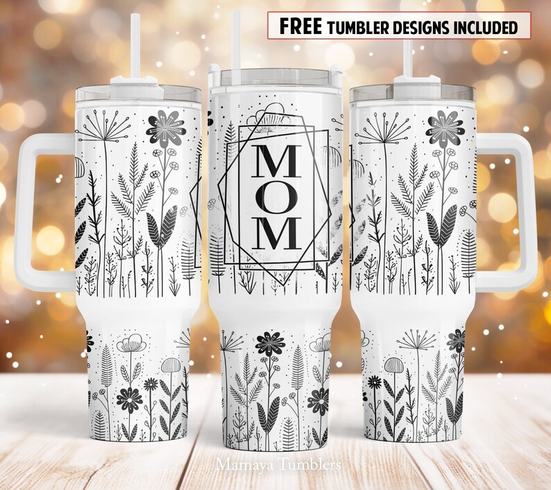 May include: White stainless steel tumbler with a black and white floral design and the word "MOM" in a geometric frame. The tumbler has a lid and a handle.