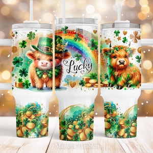 May include: White tumbler with a green, gold, and rainbow design featuring a cartoon highland cow with a shamrock and the word "Lucky".