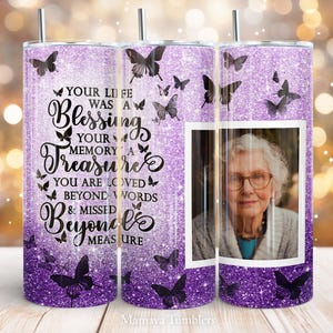 May include: Purple glitter tumbler with a black butterfly design and a photo of an older woman. The tumbler has the text "Your life was a blessing, your memory a treasure, you are loved beyond words & missed beyond measure".