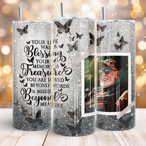 May include: A silver glitter tumbler with a black butterfly design and the text "Your life was a blessing, your memory a treasure, you are loved beyond words & missed beyond measure". A photo of a man with sunglasses is in the center of the tumbler.