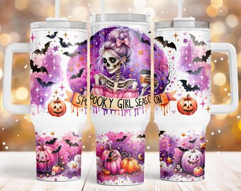 May include: A white tumbler with a purple and pink watercolor design featuring a skeleton girl holding a coffee cup. The tumbler has a handle and says "Spooky Girl Season" on it. The design also includes bats, stars, and pumpkins.
