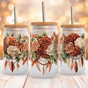 May include: Three stainless steel tumblers with lids and straws. Each tumbler features a floral design with a dreamcatcher and feathers. The flowers are in shades of red, orange, and white.
