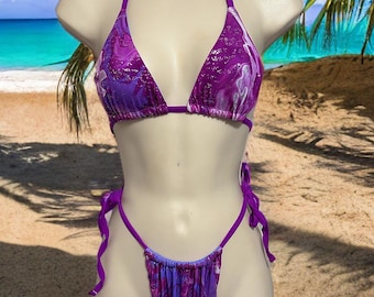 May include: Purple and white patterned bikini with a halter top and a tie-side bottom.