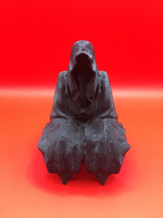 顔のない幽霊のようなフードをかぶった人物が座っている。死神の像