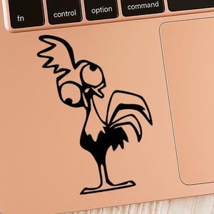 May include: A black and white cartoon rooster sticker on a rose gold laptop. The rooster has large eyes and a surprised expression. The sticker is placed on the laptop's palm rest area.