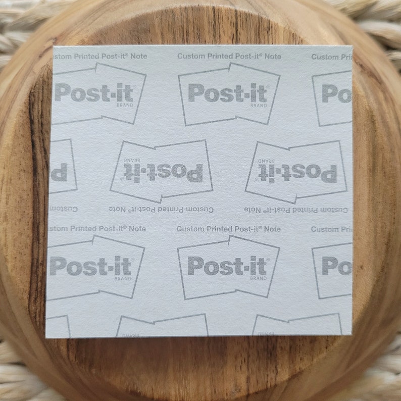 Op de afbeelding: Een wit vel papier met een herhalend patroon van het Post-it-merklogo. Het logo is in grijs gedrukt en zegt "Post-it Brand" in een wit rechthoek. De tekst "Custom Printed Post-it Note" is in grijs gedrukt bovenaan en onderaan het vel.