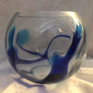 May include: A clear glass bowl with blue and white swirls. The bowl is round and has a wide opening.