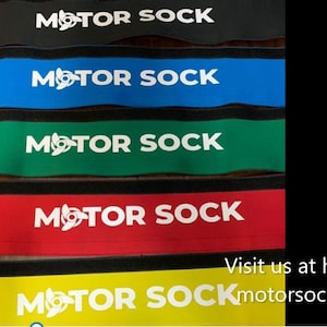 Puede incluir: Cinco pulseras de tela de colores con el texto "MOTOR SOCK" en letras blancas. Las pulseras son negras, azules, verdes, rojas y amarillas. El texto "Visítanos en http://motorsock.com" es visible en la parte inferior de la imagen.