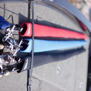 May include: Three fishing rods are stored in a boat, each with a protective sleeve. The sleeves are black, blue, and red, and each has the word "Y-TIGER" printed on it.