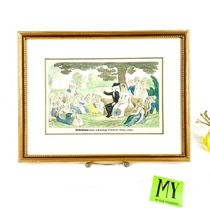 Peut inclure: Une estampe ancienne encadrée représentant une illustration satirique d'un groupe de femmes dans un jardin. Le texte sous l'image indique "DR SYNTAX visits a Boarding School for Young Ladies."