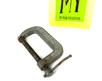 May include: A silver metal C-clamp with a threaded screw and a handle. The clamp is labelled "STEELCRAFT".