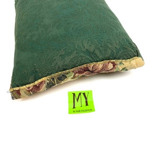 May include: A green pillow with a floral pattern on the border. The pillow has a textured surface and is made of a soft fabric. The pillow is labeled "MY 40 YEAR COLLECTION".