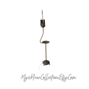 May include: A vintage floor lamp with a bronze finish. The lamp features a three-light fixture, a small circular tray, and a decorative base. The lamp's design includes a curved stem and a detailed, ornate base. The Etsy shop name "My4NearCollection.Etsy.Com" is at the bottom.