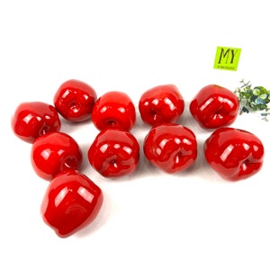 May include: Ten shiny red apples arranged on a white surface. The apples are all the same size and shape, and they are arranged in a random pattern.