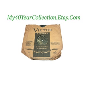 May include: A brown paper record sleeve with the text "VICTOR RECORDS" printed in black. The sleeve has a black and gold label with the text "DECCA" and the words "The World's Greatest Artists are on Victor Records".