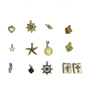 May include: A collection of small, decorative charms in various shapes, including a heart, star, starfish, and ship's wheel. The charms are in gold, silver, and bronze tones, with some featuring intricate details and embellishments. Ideal for jewelry making.
