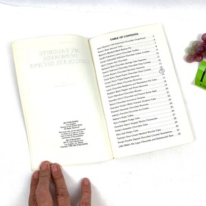 May include: An open book with a white cover and black text. The book is titled "My Favorite Homemade Chocolate Recipes". The table of contents lists various chocolate recipes, including chocolate gingerbreads, truffles, cakes, and cookies.