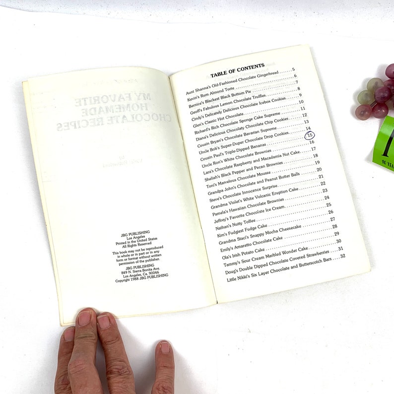 May include: An open book with a white cover and black text. The book is titled "My Favorite Homemade Chocolate Recipes". The table of contents lists various chocolate recipes, including chocolate gingerbreads, truffles, cakes, and cookies.