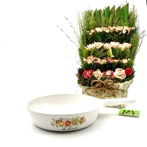 May include: White ceramic skillet with a green and brown floral design and the text "Le Persil". The skillet has a handle and is empty.