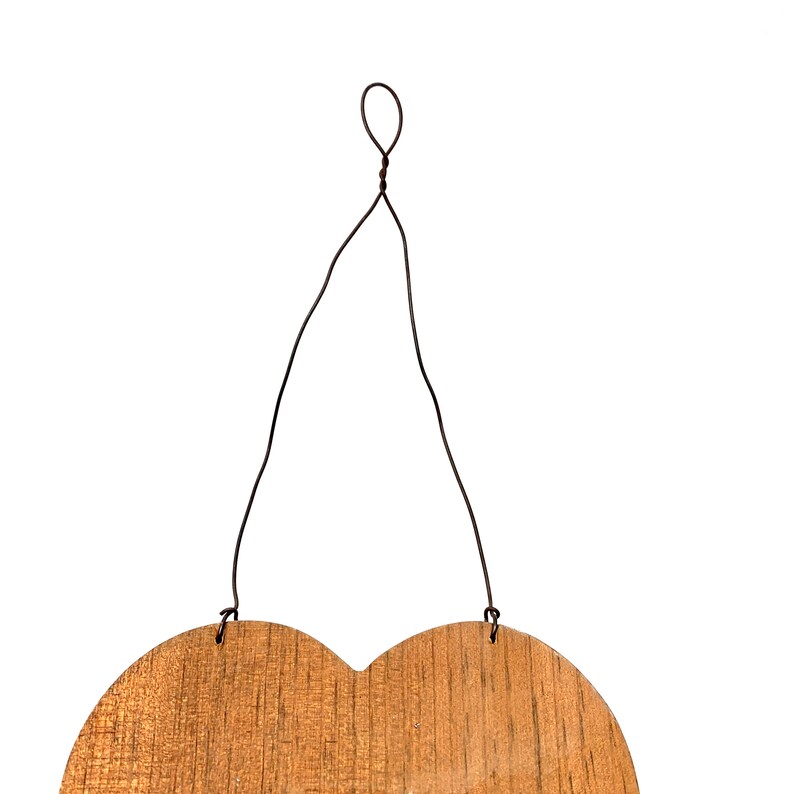 May include: A wooden heart-shaped sign with a brown wire hanger. The sign is blank and ready to be decorated.
