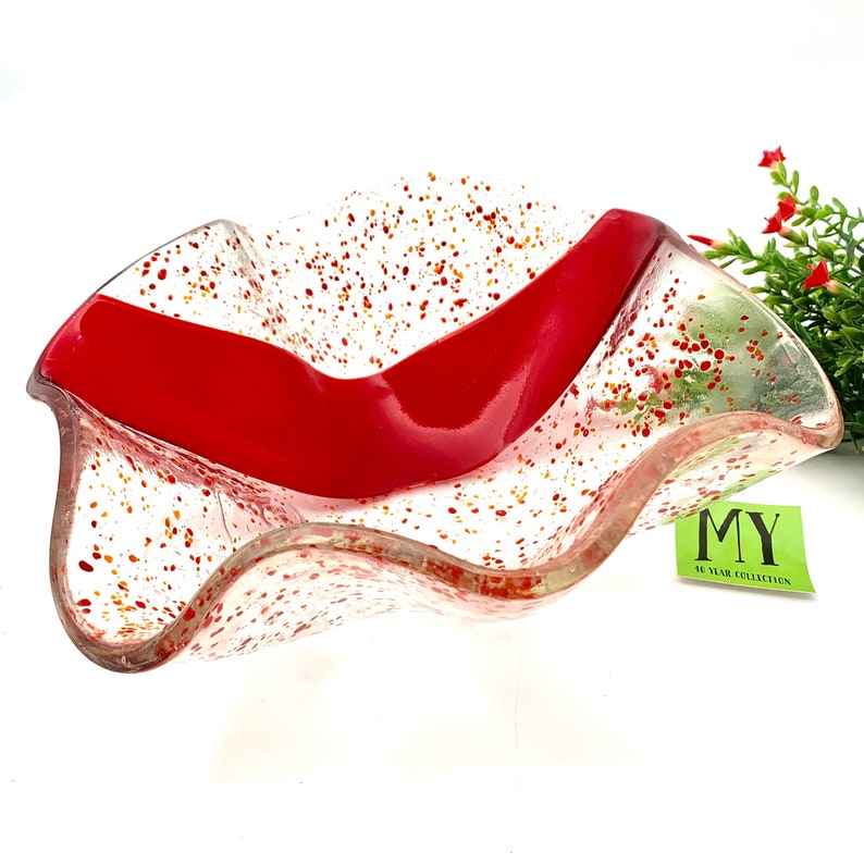 K&ouml;nnte beinhalten: Eine klare Glassch&uuml;ssel mit einem roten Streifen und orangefarbenen und roten Flecken. Die Sch&uuml;ssel hat einen gewellten Rand und steht auf einer wei&szlig;en Oberfl&auml;che. Der Text "MY 40 YEAR COLLECTION" befindet sich auf einem gr&uuml;nen Etikett.