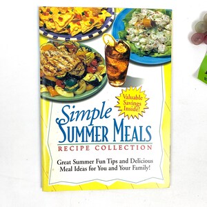 May include: A yellow and white cookbook with the title "Simple Summer Meals Recipe Collection". The cover features a photo of grilled chicken, vegetables, chips and dip, a salad, and iced tea.