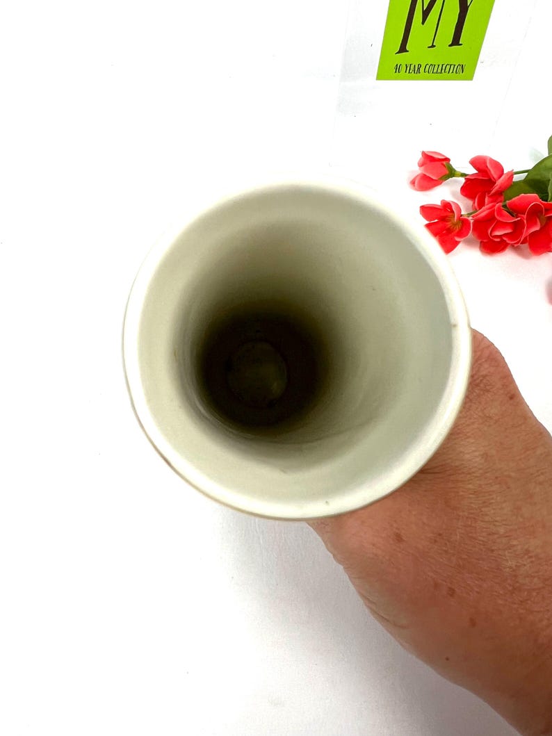 May include: The inside of a white ceramic vase. The vase is tall and narrow, with a smooth, glossy finish.