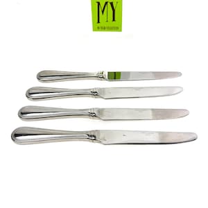 May include: Four silver-colored knives with a decorative handle design. The blades are smooth and shiny. The knives are arranged on a white background. A green square with the text "MY 40 YEAR COLLECTION" is in the upper left corner.