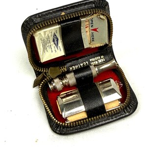 May include: Vintage black leather travel shaving kit with a zipper closure. The kit contains a Gillette safety razor, blades, and a small strop. The interior is lined with red fabric. The case is marked "CASE MADE LEATHER AUSTRIA".