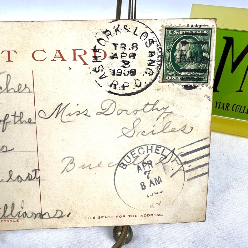May include: Antique postcard featuring a green one-cent stamp and postmarks from Los Angeles and Buechel, KY, dated April 1909. The postcard is addressed to Miss Dorothy Sciles.