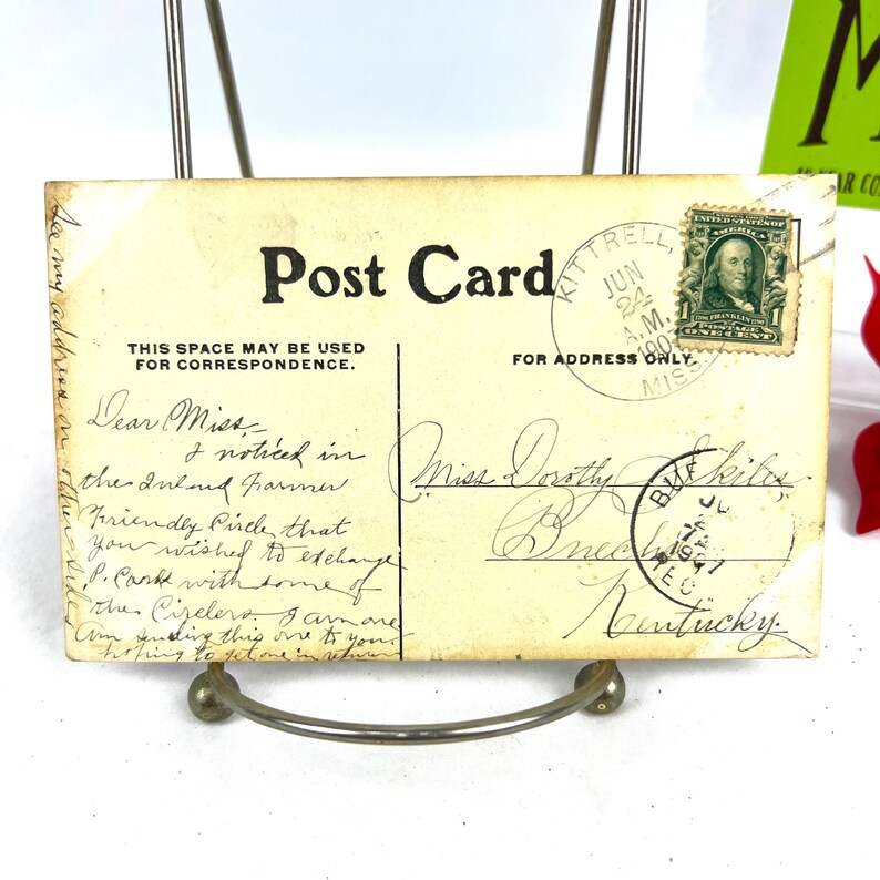 K&ouml;nnte beinhalten: Eine Vintage-Postkarte mit einer handschriftlichen Nachricht. Die Postkarte ist cremefarben mit einem schwarzen Rand und den Worten "Post Card" in Schwarz gedruckt. Die Nachricht lautet: "Liebe Miss, ich habe im Inland Farmer bemerkt. Friendly Circle, dass Sie f. Cark mit einigen der Cizelero austauschen wollten. Ich bin einer davon. Ich schicke Ihnen diesen hier und hoffe, einen im Gegenzug zu bekommen." Die Postkarte hat eine Briefmarke mit einem Portr&auml;t von George Washington und den Worten "United States Postage" darauf gedruckt. Die Briefmarke ist mit "Jun 24, 1900 A.M. Kittrell, Miss." abgestempelt.