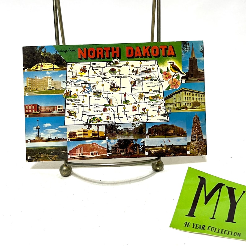 May include: A vintage postcard featuring a map of North Dakota with various images of landmarks and cities. The postcard has the text "Greetings from North Dakota" at the top.