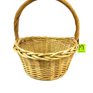 May include: A natural woven wicker basket with a single handle. The basket is light brown in color and has a rounded shape.