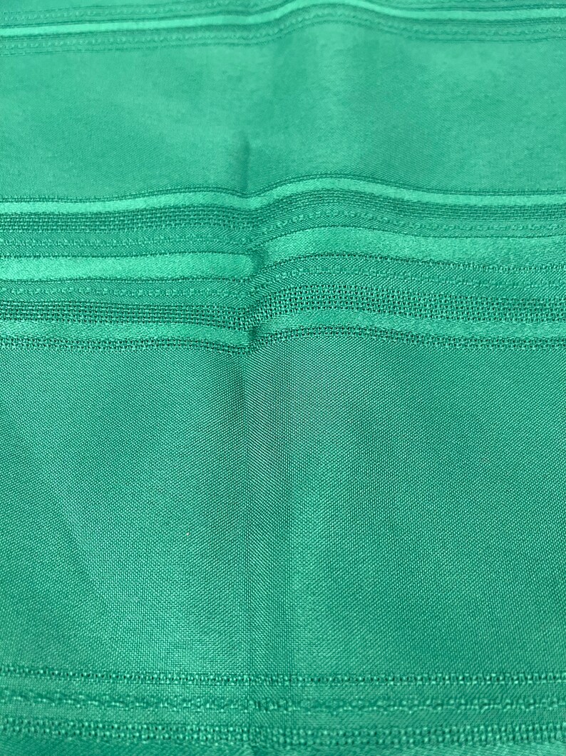 May include: A close-up of a teal fabric with horizontal stripes. The fabric has a subtle sheen and a textured surface.