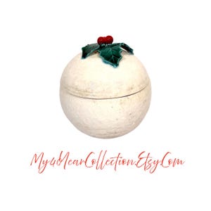 May include: A round, off-white ceramic container with a lid, topped with a holly leaf and red berry design. The container has a textured surface and a visible seam where the lid meets the base. The text "My4YearCollection.Etsy.Com" is at the bottom.