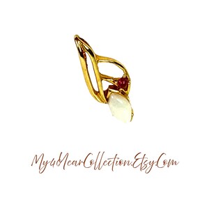 Könnte beinhalten: Goldfarbener Anhänger in Blattform mit einem weißen Edelstein und zwei kleinen roten Edelsteinen. Der Anhänger hat eine Schlaufe für eine Kette. Der Text "My4NearCollection.Etsy.Com" befindet sich unten.