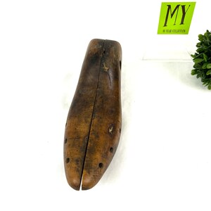 May include: A wooden shoe stretcher with a brown finish. The stretcher is split in half and has a series of holes along the sides.