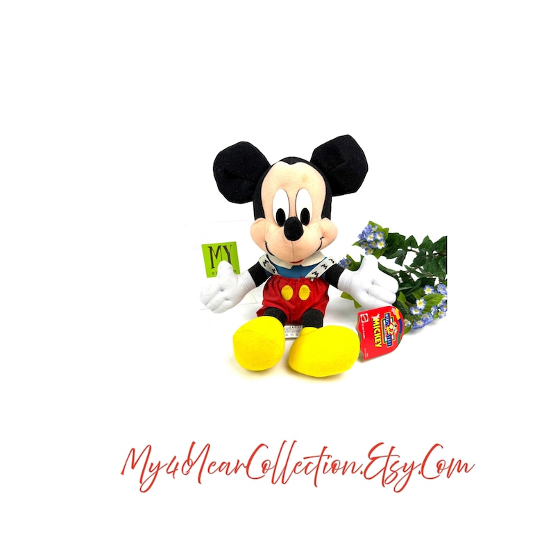 Vintage Mattel Mickey’s Stuff for Kids plush toy sitting upright with yellow shoes and original tag, displayed against a white background with flowers
