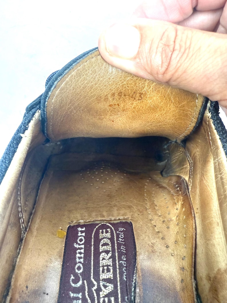 May include: Close-up of the inside of a dark blue shoe. The interior is tan leather with a brown label that reads "VERDE made in italy". The shoe's interior shows signs of wear.