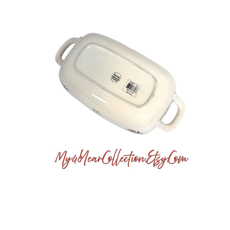 Pu&ograve; includere: Piatto da portata rettangolare bianco sporco con due manici. Il lato inferiore del piatto &egrave; visibile, con l'etichetta del produttore e un motivo floreale. Il piatto ha un aspetto leggermente invecchiato.