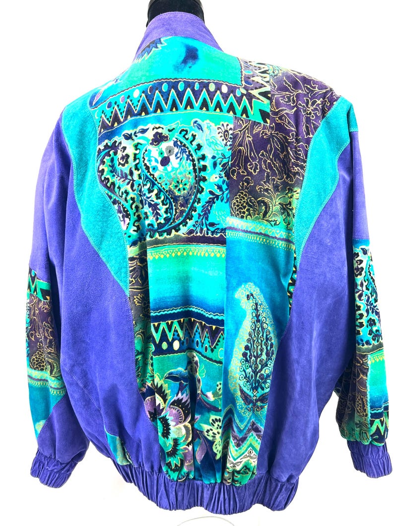 May include: A purple suede jacket with a colorful patchwork design featuring paisley patterns, geometric shapes, and floral motifs.