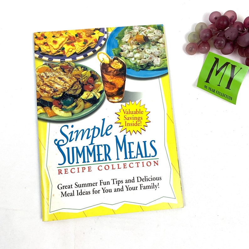 May include: A yellow and green cookbook with the title "Simple Summer Meals Recipe Collection". The cover features photos of food, including a salad, grilled chicken, and a glass of iced tea.