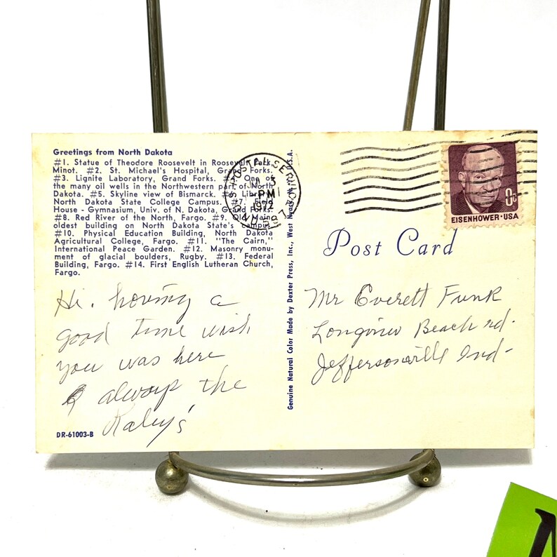 May include: A vintage postcard with a handwritten message that reads "Hi. houng a good time wish you was here & always the Kalys". The postcard is addressed to Mr. Everett Funk, Longview Beach rd. Jeffersonville Ind. The postcard has a stamp with a portrait of President Eisenhower.