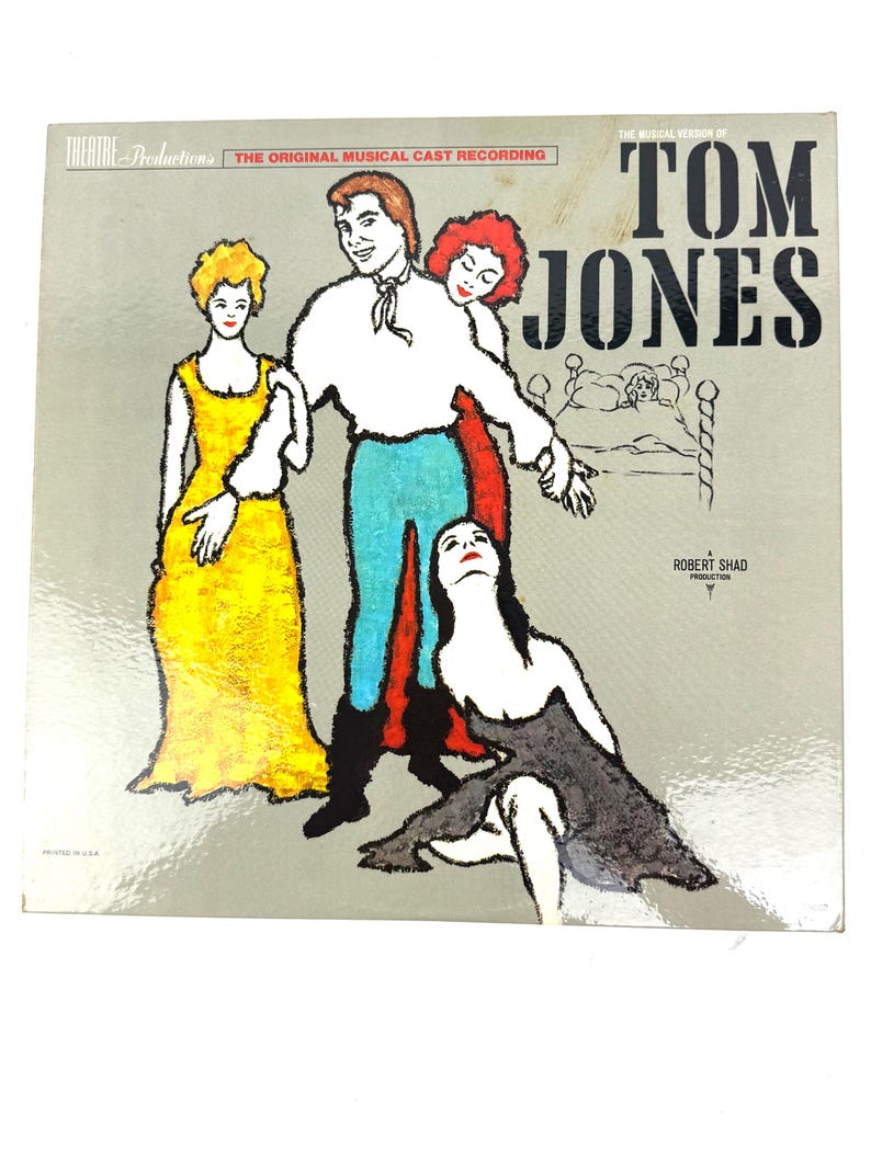 Puede incluir: Funda de vinilo vintage para "Tom Jones", una producci&oacute;n musical. La portada presenta una ilustraci&oacute;n estilizada de personajes en colores vibrantes: un hombre en blanco y azul, dos mujeres en amarillo y rojo y una mujer en negro. El texto incluye "Theatre Productions" y "The Original Musical Cast Recording."