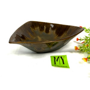 May include: A triangular ceramic serving bowl with a brown and green glaze. The bowl has a unique, wavy design and a glossy finish.