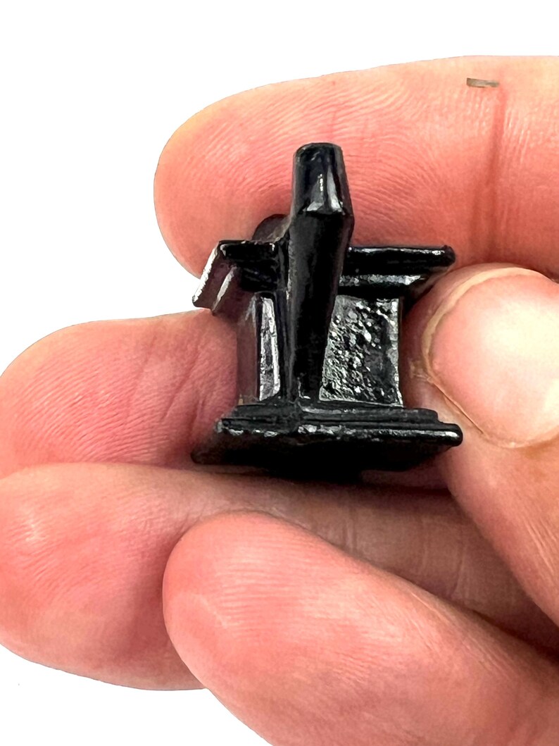 May include: A small, black, plastic miniature of a church building. The church has a pointed roof and a cross on top.